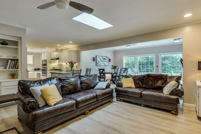 3002 Stardust Dr, Austin, TX 78757 - living room featuring ornamental molding, light wood finished floors, ceiling fan, a skylight, and recessed lighting