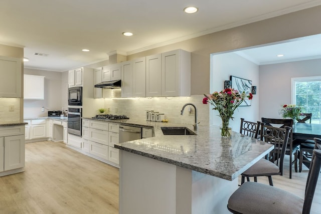 3002 Stardust Dr, Austin, TX 78757 - kitchen with a sink, appliances with stainless steel finishes, a peninsula, a kitchen breakfast bar, and light wood-style floors