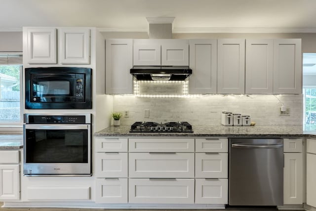 3002 Stardust Dr, Austin, TX 78757 - kitchen featuring appliances with stainless steel finishes, under cabinet range hood, crown molding, backsplash, and light stone counters