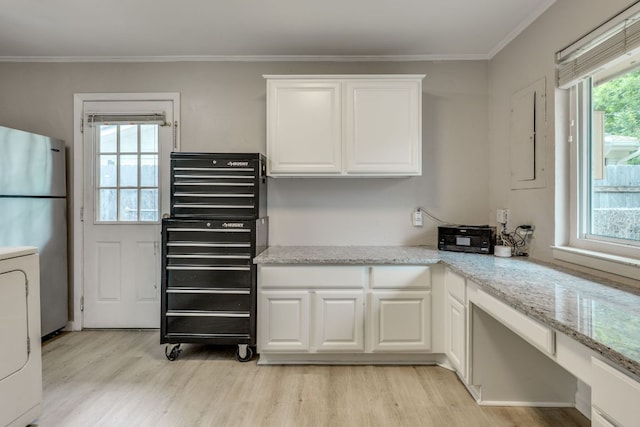 3002 Stardust Dr, Austin, TX 78757 - kitchen with freestanding refrigerator, light wood finished floors, washer / dryer, white cabinetry, and crown molding