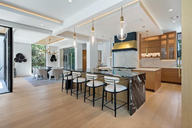 1115 Gillespie Pl, Austin, TX 78704 - kitchen with modern cabinets, range hood, a large island with sink, tasteful backsplash, and a breakfast bar