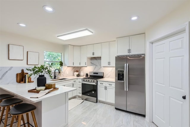 5403 Village Ln, Austin, TX 78744 - kitchen with appliances with stainless steel finishes, a sink, a breakfast bar, a peninsula, and white cabinetry