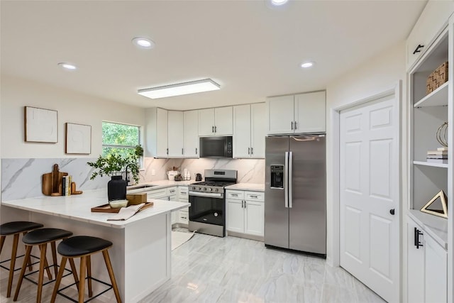 5403 Village Ln, Austin, TX 78744 - kitchen with appliances with stainless steel finishes, a peninsula, white cabinetry, backsplash, and recessed lighting