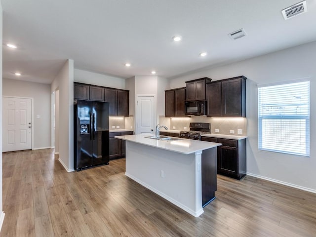 204 Magione St, Hutto, TX 78634 - kitchen with black appliances, a sink, dark brown cabinetry, backsplash, and light wood-type flooring