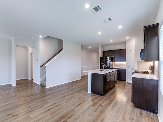 204 Magione St, Hutto, TX 78634 - kitchen with dark brown cabinetry, light wood-type flooring, black appliances, light countertops, and recessed lighting