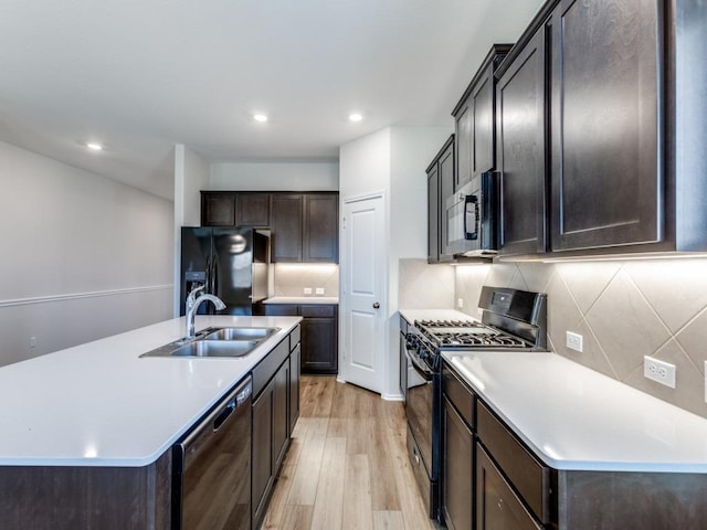 204 Magione St, Hutto, TX 78634 - kitchen featuring black appliances, a sink, light wood-style flooring, decorative backsplash, and dark brown cabinets