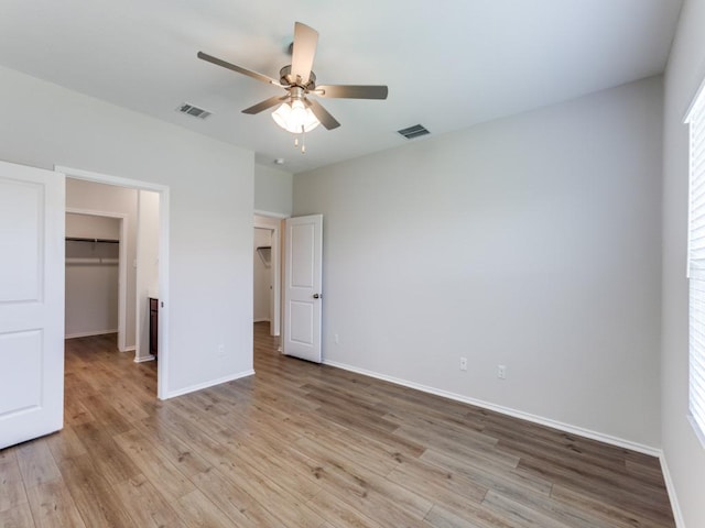 204 Magione St, Hutto, TX 78634 - unfurnished bedroom with light wood-style flooring, a spacious closet, a closet, baseboards, and a ceiling fan