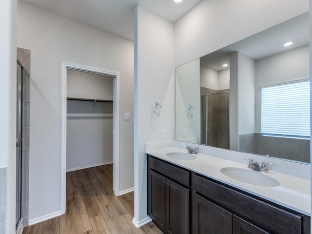 204 Magione St, Hutto, TX 78634 - bathroom with a shower stall, a walk in closet, double vanity, wood finished floors, and baseboards