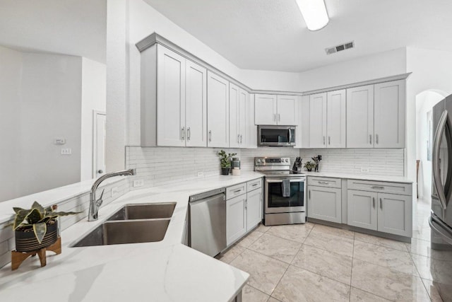 6015 Lone Star Ct, Hutto, TX 78634 - kitchen featuring stainless steel appliances, gray cabinetry, a sink, and backsplash