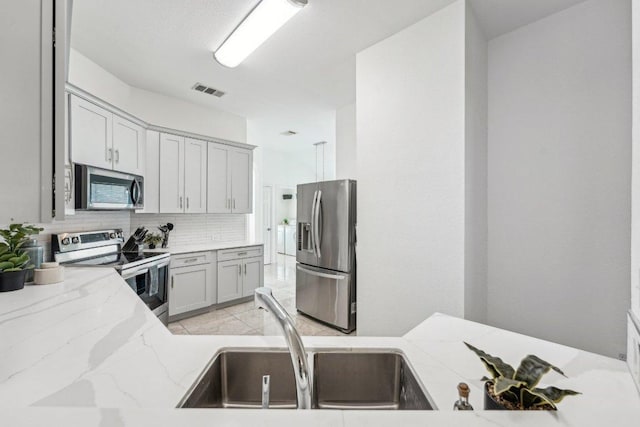 6015 Lone Star Ct, Hutto, TX 78634 - kitchen featuring stainless steel appliances, light stone countertops, and backsplash