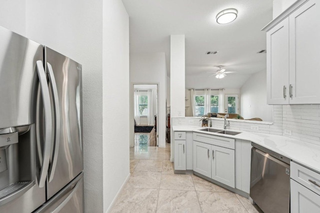 6015 Lone Star Ct, Hutto, TX 78634 - kitchen with stainless steel appliances, a sink, tasteful backsplash, a ceiling fan, and light stone countertops