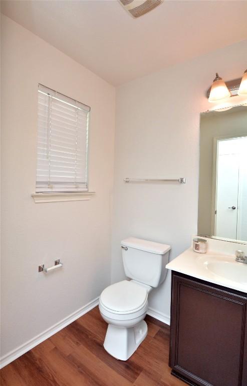 1902 Tranquilo Trl, Austin, TX 78744 - half bath featuring wood finished floors, vanity, baseboards, and toilet
