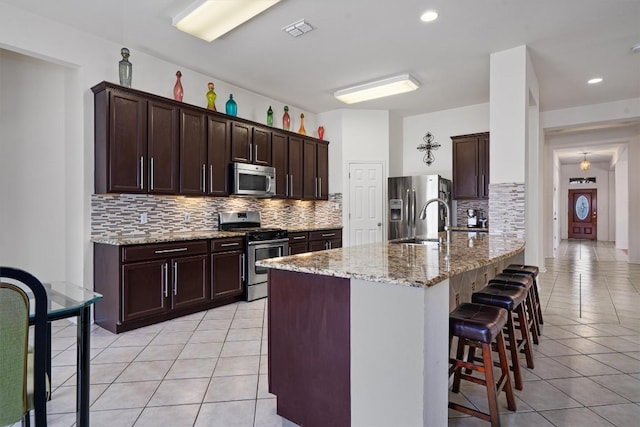 15617 Staffordshire Ln, Austin, TX 78717 - kitchen with stainless steel appliances, light tile patterned floors, decorative backsplash, and a kitchen bar