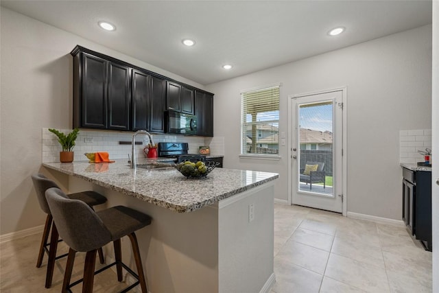 212 Canis St, Georgetown, TX 78628 - kitchen featuring black microwave, a sink, range, tasteful backsplash, and a breakfast bar