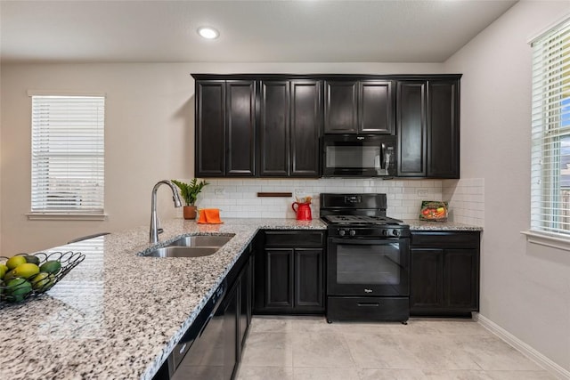212 Canis St, Georgetown, TX 78628 - kitchen with black appliances, a sink, dark cabinetry, tasteful backsplash, and light stone counters