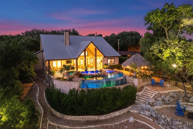 17505 E Darleen Dr, Leander, TX 78641 - rear view of house featuring a hot tub, a chimney, an outdoor pool, metal roof, and a patio area