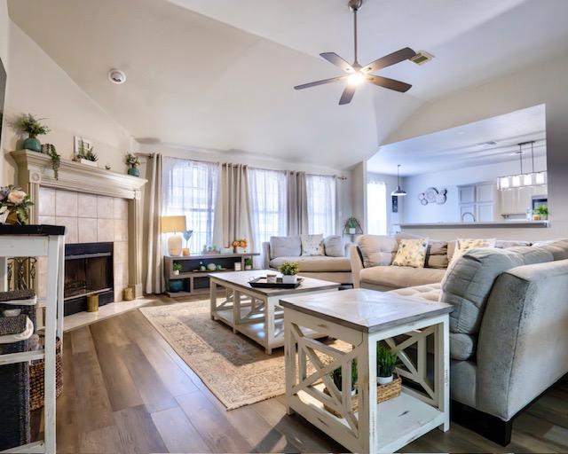 1406 Apache Cv, Pflugerville, TX 78660 - living area with vaulted ceiling, ceiling fan, dark wood finished floors, and a tiled fireplace