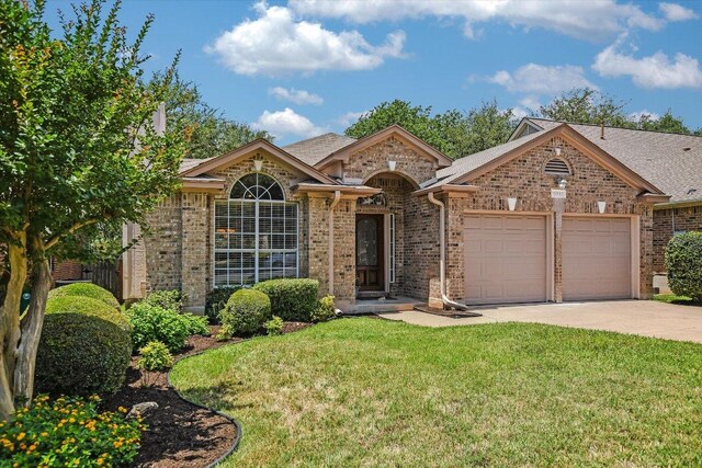 10902 Sierra Oaks, Austin, TX 78759 - view of front facade with an attached garage, brick siding, concrete driveway, and a front lawn