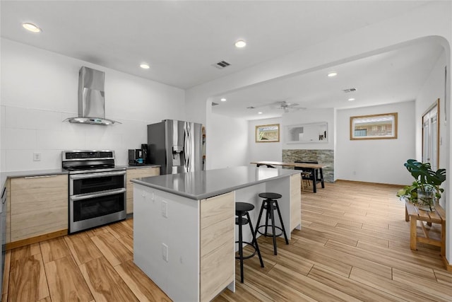 504 Tyree Rd, Cedar Park, TX 78613 - kitchen featuring appliances with stainless steel finishes, wall chimney range hood, modern cabinets, light wood-style floors, and a fireplace