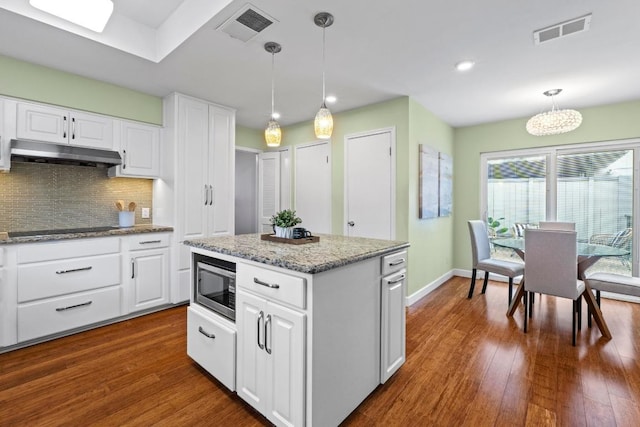 8126 Greenslope Dr, Austin, TX 78759 - kitchen with stainless steel microwave, under cabinet range hood, black electric cooktop, dark wood-type flooring, and recessed lighting