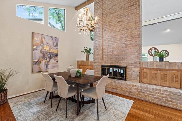 8126 Greenslope Dr, Austin, TX 78759 - dining area with wood finished floors, a brick fireplace, a towering ceiling, a chandelier, and baseboards
