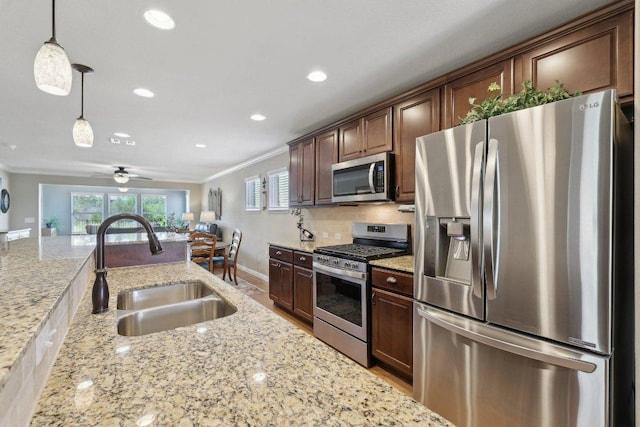 709 Kitty Hawk Rd, Georgetown, TX 78633 - kitchen featuring appliances with stainless steel finishes, a sink, ornamental molding, pendant lighting, and light stone counters