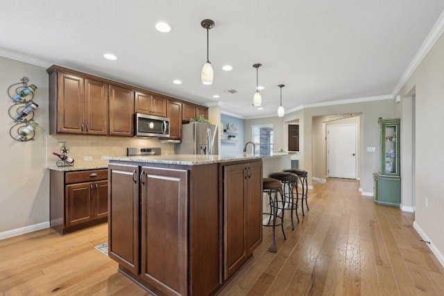 709 Kitty Hawk Rd, Georgetown, TX 78633 - kitchen with appliances with stainless steel finishes, a center island with sink, baseboards, light wood-style floors, and crown molding