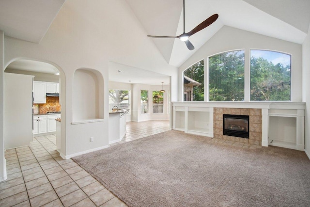 5616 Gorham Glen Ln, Austin, TX 78739 - unfurnished living room featuring a ceiling fan, light tile patterned floors, a fireplace, high vaulted ceiling, and light carpet