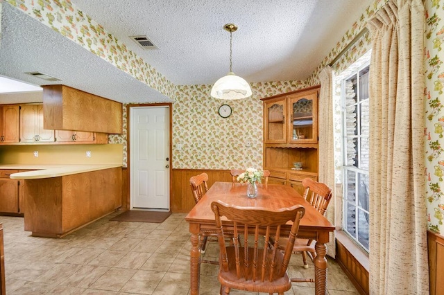 301 Navajo Trl, Georgetown, TX 78633 - dining area featuring plenty of natural light, wainscoting, a textured ceiling, wallpapered walls, and wood walls