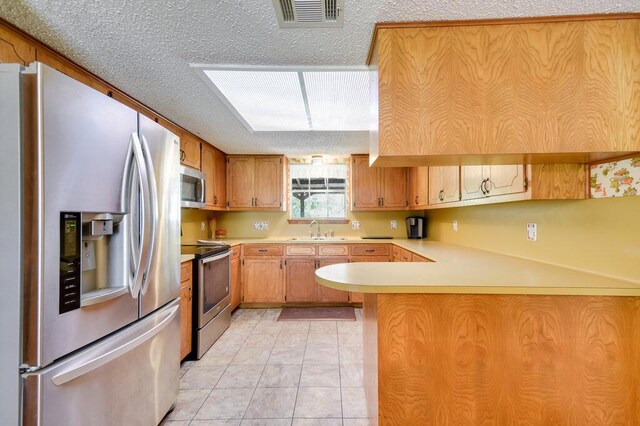 301 Navajo Trl, Georgetown, TX 78633 - kitchen featuring stainless steel appliances, a sink, light countertops, a peninsula, and a textured ceiling