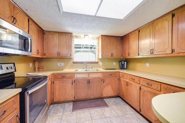 301 Navajo Trl, Georgetown, TX 78633 - kitchen with stainless steel appliances, a sink, a textured ceiling, light countertops, and light tile patterned floors