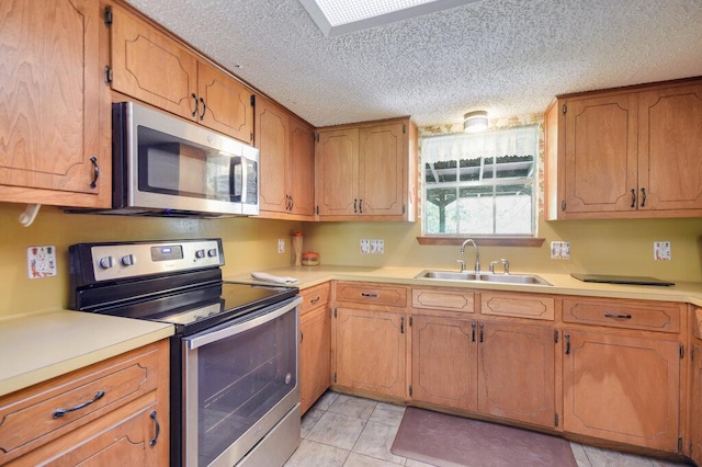 301 Navajo Trl, Georgetown, TX 78633 - kitchen with stainless steel appliances, a sink, a textured ceiling, light countertops, and light tile patterned floors