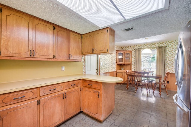 301 Navajo Trl, Georgetown, TX 78633 - kitchen featuring wallpapered walls, a textured ceiling, freestanding refrigerator, wainscoting, and a peninsula