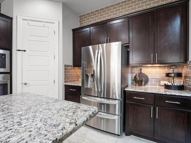 116 Claiborne Lake Ln, Georgetown, TX 78628 - kitchen featuring appliances with stainless steel finishes, light stone counters, backsplash, light tile patterned floors, and dark brown cabinets