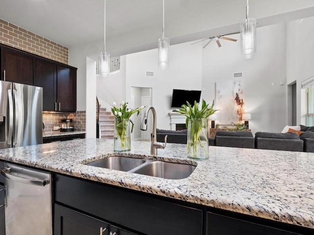 116 Claiborne Lake Ln, Georgetown, TX 78628 - kitchen featuring open floor plan, a high ceiling, light stone counters, stainless steel appliances, and hanging light fixtures