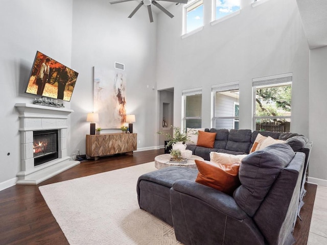 116 Claiborne Lake Ln, Georgetown, TX 78628 - living room featuring a high ceiling, ceiling fan, wood finished floors, and a warm lit fireplace