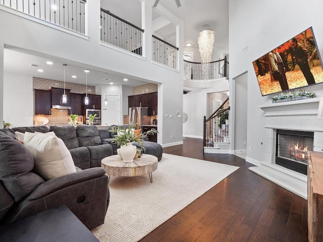 116 Claiborne Lake Ln, Georgetown, TX 78628 - living area featuring a towering ceiling, stairway, dark wood-type flooring, and a warm lit fireplace