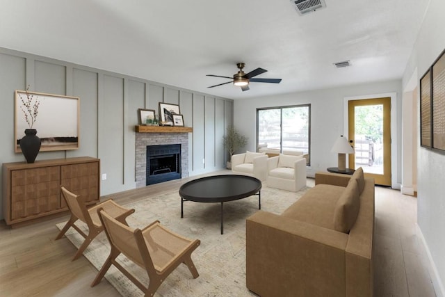 7702 Turquoise Trl, Austin, TX 78749 - living area with a fireplace, light wood finished floors, a decorative wall, and a ceiling fan