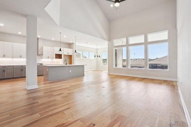 16825 Roselin Dr, Austin, TX 78738 - unfurnished living room with light wood finished floors, baseboards, a sink, recessed lighting, and a high ceiling