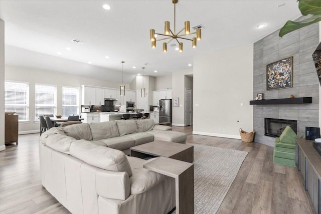 1504 Saddlespur Ln, Leander, TX 78641 - living room featuring light wood-type flooring, a chandelier, baseboards, a fireplace, and recessed lighting