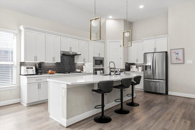 1504 Saddlespur Ln, Leander, TX 78641 - kitchen with appliances with stainless steel finishes, under cabinet range hood, baseboards, a kitchen island with sink, and recessed lighting