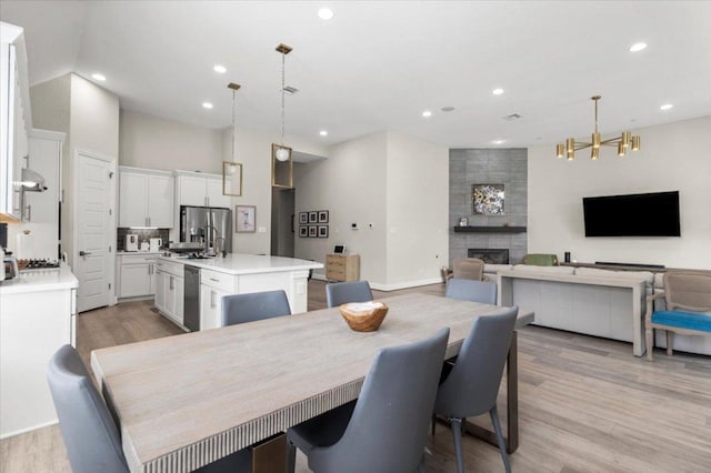 1504 Saddlespur Ln, Leander, TX 78641 - dining room featuring a fireplace, recessed lighting, light wood-style floors, and a chandelier