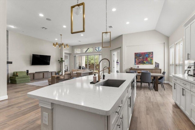 1504 Saddlespur Ln, Leander, TX 78641 - kitchen with an island with sink, light wood-style floors, white cabinetry, recessed lighting, and vaulted ceiling