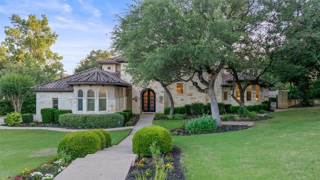 104 Sendera Bonita, Lakeway, TX 78734 - mediterranean / spanish-style house with french doors, stone siding, a front yard, a tiled roof, and stucco siding