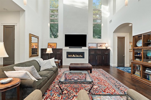 104 Sendera Bonita, Lakeway, TX 78734 - living room with a towering ceiling, dark wood finished floors, a warm lit fireplace, and arched walkways