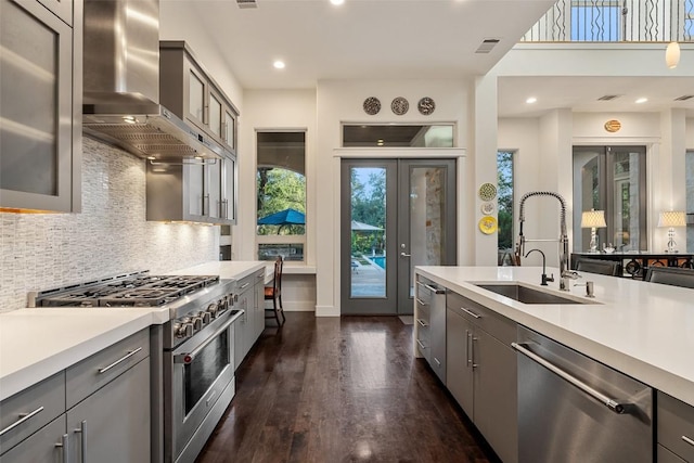 104 Sendera Bonita, Lakeway, TX 78734 - kitchen featuring appliances with stainless steel finishes, wall chimney exhaust hood, gray cabinetry, light countertops, and recessed lighting