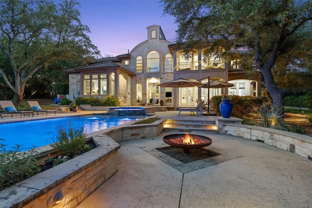 104 Sendera Bonita, Lakeway, TX 78734 - back of property featuring a fire pit, a patio, stucco siding, a balcony, and a pool with connected hot tub