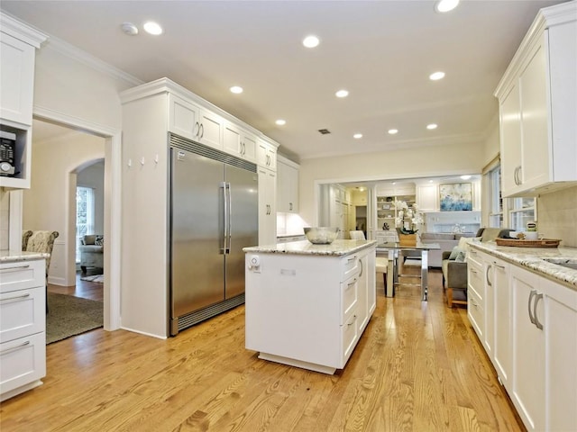 203 Wallis Dr, Austin, TX 78746 - kitchen featuring built in fridge, ornamental molding, a kitchen island, arched walkways, and white cabinets