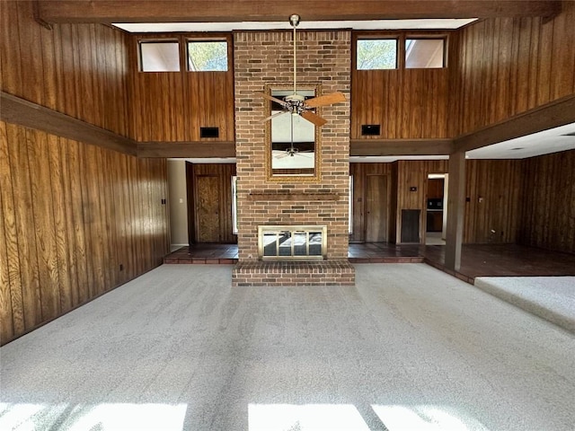2804 Rock Way, Austin, TX 78746 - unfurnished living room with wood walls, a towering ceiling, ceiling fan, carpet, and a brick fireplace