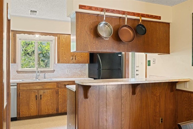 1012 Chesapeake Dr, Austin, TX 78758 - kitchen featuring freestanding refrigerator, a sink, brown cabinets, a textured ceiling, and light countertops